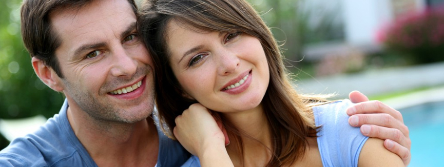 Cheerful couple sitting in front of new house